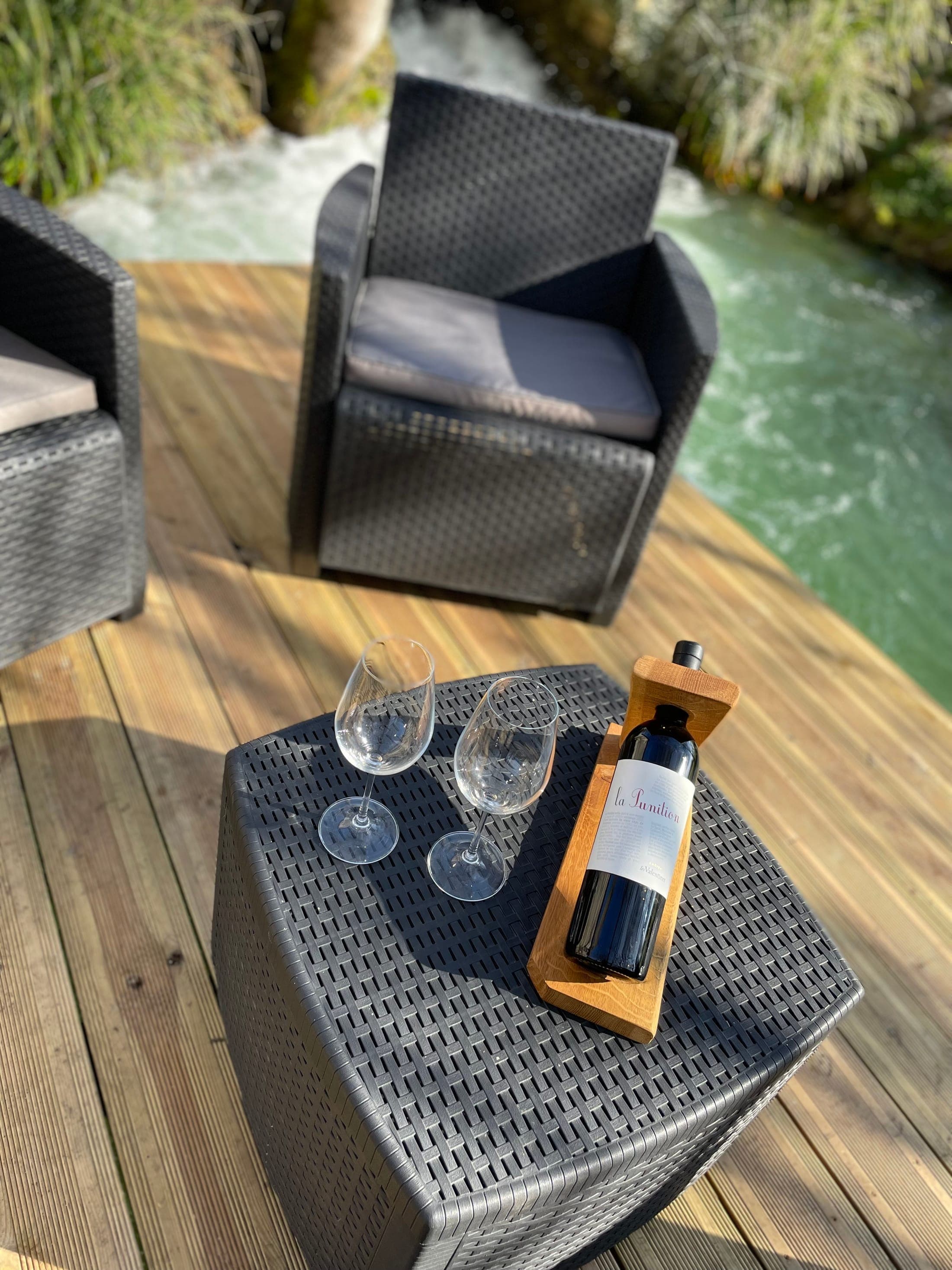 Coin salon extérieur sur la terrasse, verres et bouteille de vin, vue sur la rivière
